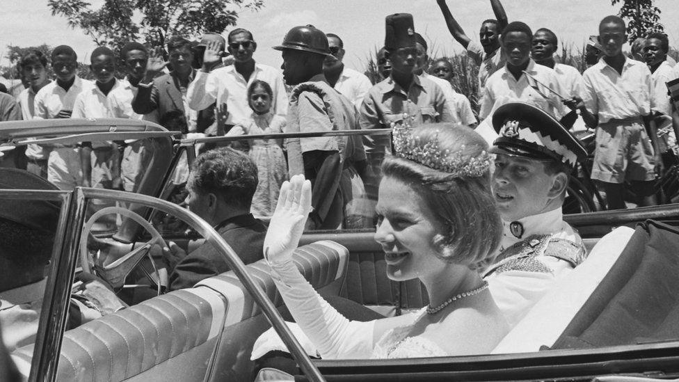 The Duchess of Kent is seen waving from her car at Uganda's independence celebrations in 1962