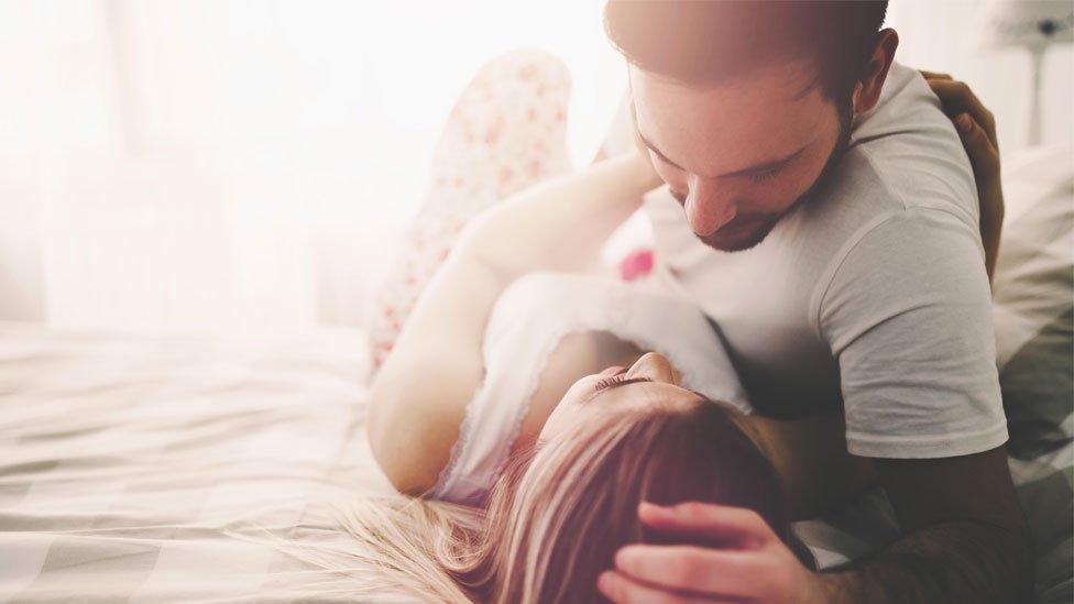 A stock image of a couple lying together in bed