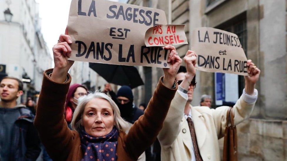 A man and a woman carry placards in the street