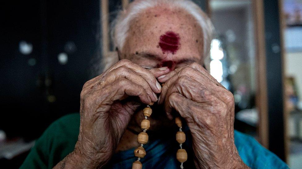 Susheela B holds holy beads in her hands as she prays