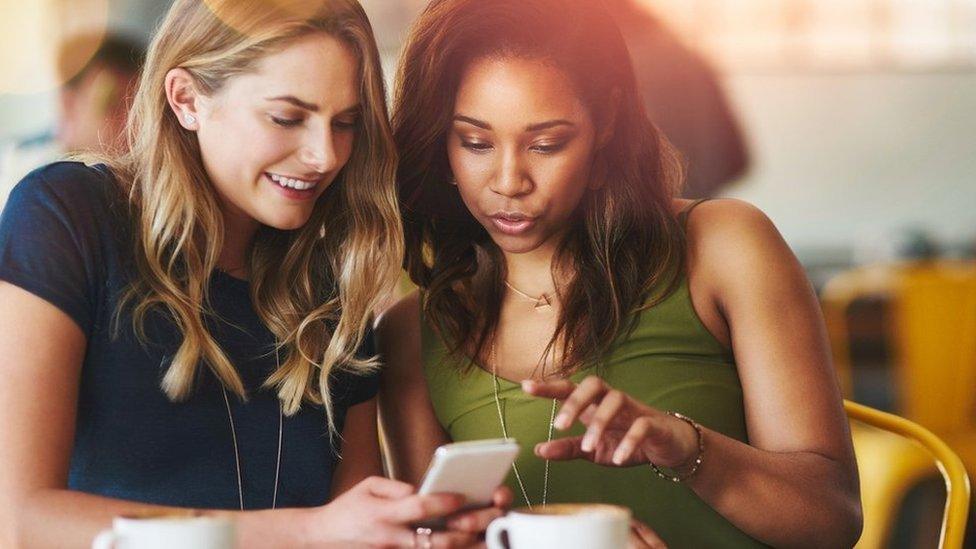 Two women look at a mobile phone