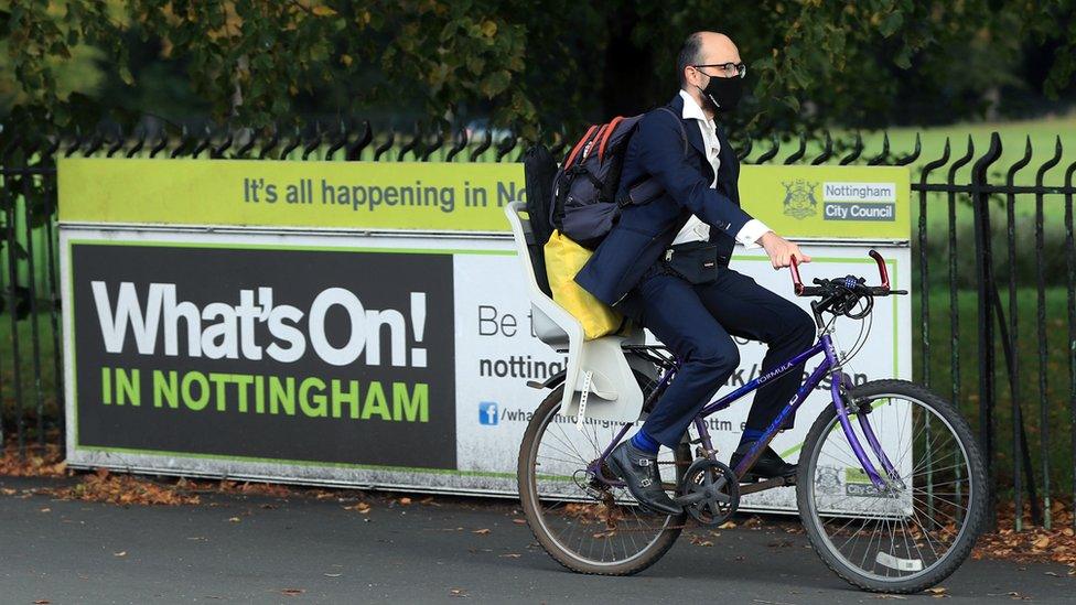 Man on a bike going past a What's On in Nottingham sign