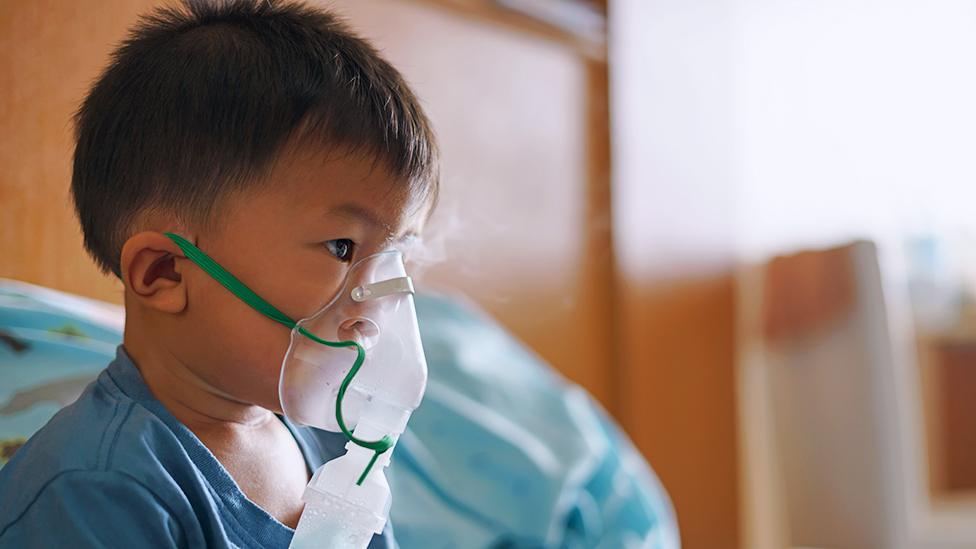 A boy using an inhaler to stop coughing