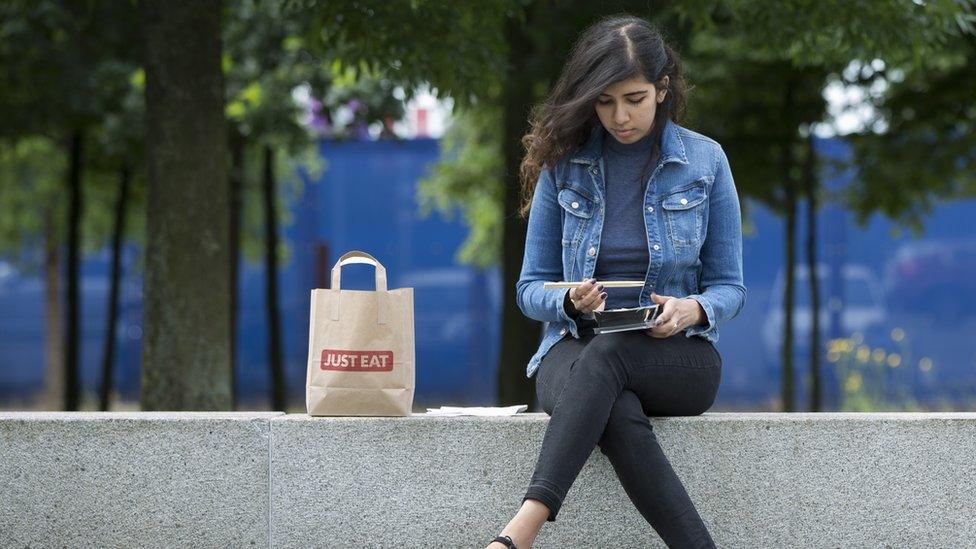 Woman eating Just Eat takeaway