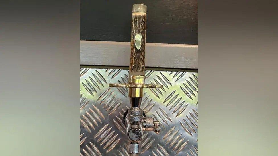 Decorative beer pump with a wooden handle, designed to look like the handle of a knife