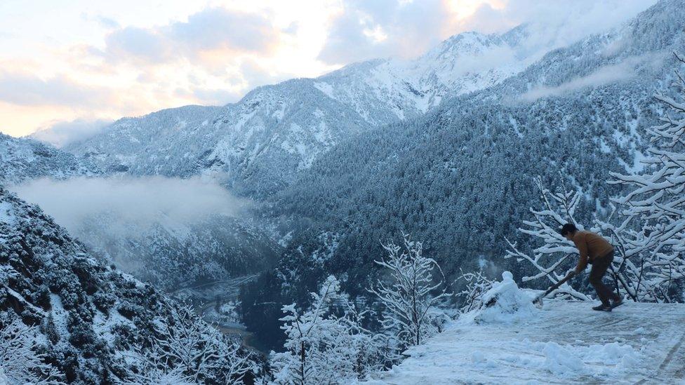 A boy removes snow from his house in Neelum valley, Pakistani administered Kashmir, 14 January 2020