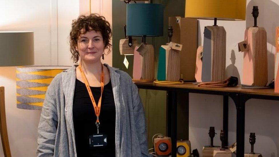 Beck Prior standing in her shop with wooden lamps behind her