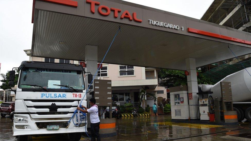 A worker anchors the roof of a fuel station to a mixer truck as Super Typhoon Mangkhut approaches the city of Tuguegarao