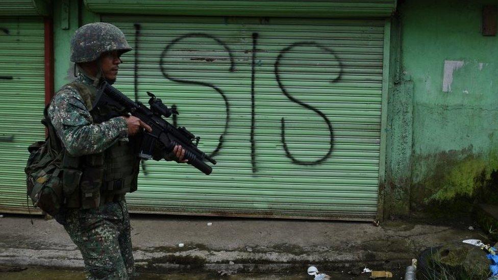 A Philippine Marine walks past graffiti during a patrol along a deserted street at the frontline in Marawi, on the southern island of Mindanao on 22 July 2017.