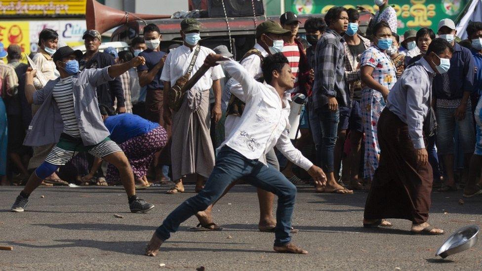 Pro-military supporters hurl stones at residents near the central railway station in Yangon, Myanmar