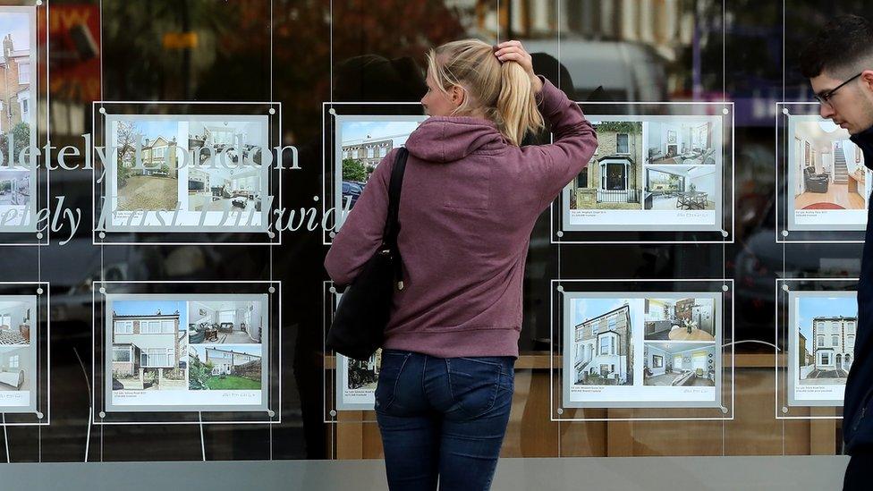 A woman looks in an estate agent's window in London, England.