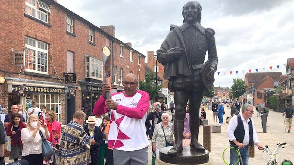 Baton bearer in Stratford-upon-Avon with William Shakespeare statue