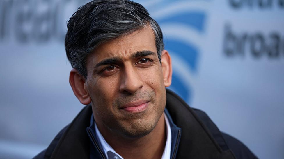 Rishi Sunak stands in front of a white van while giving an interview in Wales on 22 February