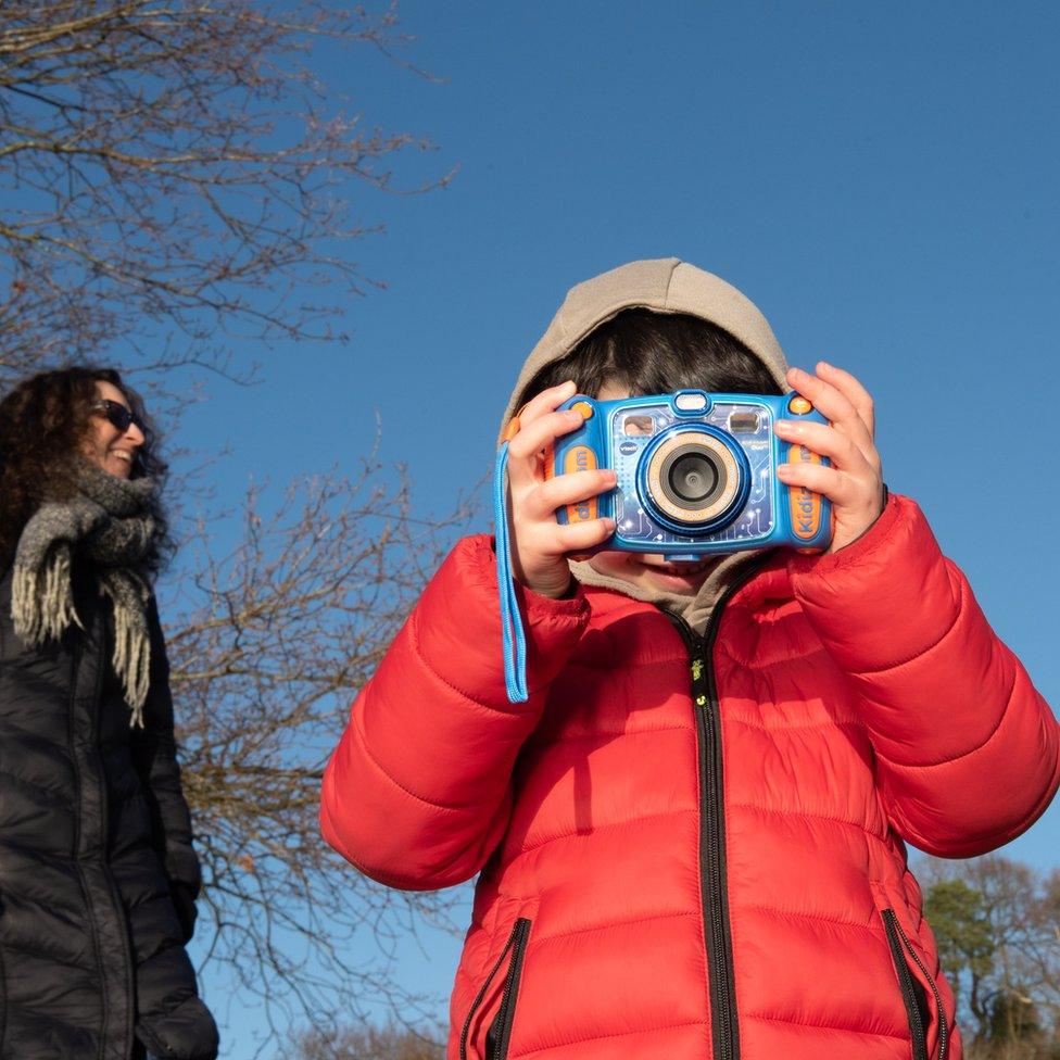 Katy and Ramona - a woman stands near a child who poses with a camera