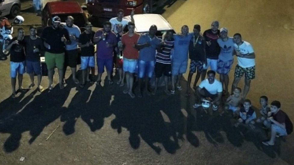 A group of people stand together giving a thumbs-up sign