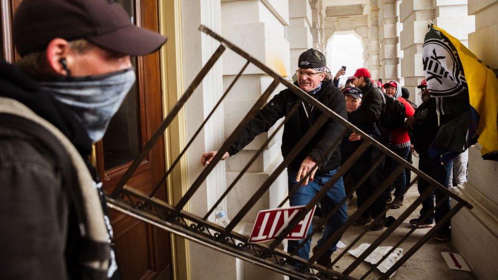 A member of a pro-Trump mob bashes an entrance of the Capitol Building in an attempt to gain access on January 6, 2021 in Washington, DC.