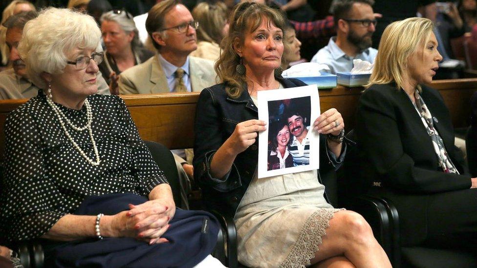 An attendee holds a photo of Cheri Domingo and her boyfriend Gregory Sanchez, who were killed in 1981, as she sits in the courtroom during the arraignment of Joseph James DeAngelo, the suspected "Golden State Killer" on April 27, 2018 in Sacramento, California.