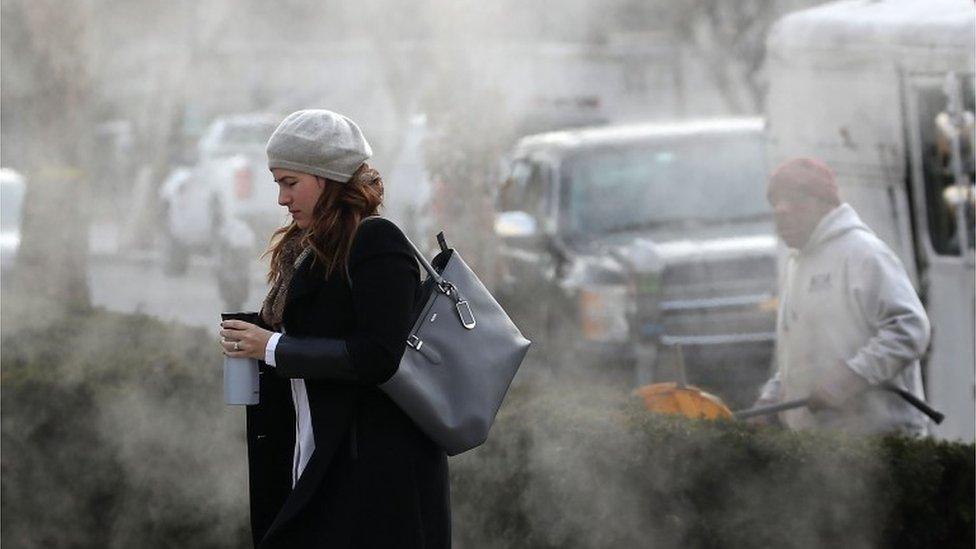 A women is bundled up as she walks past a steam grate on January 3, 2018 in Washington, DC