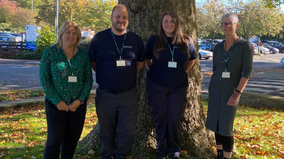 Four members of the Dog Warden service standing in front of a tree