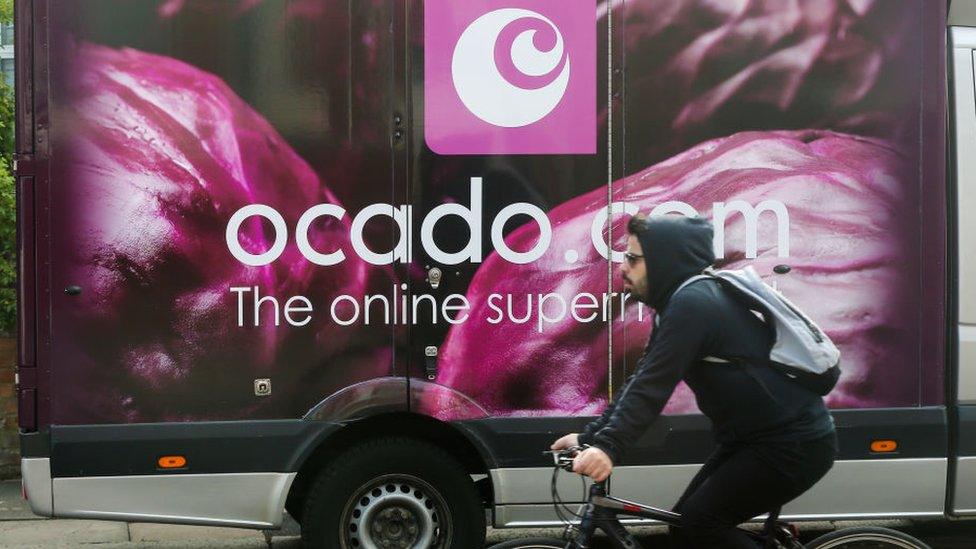 Man cycling past Ocado truck