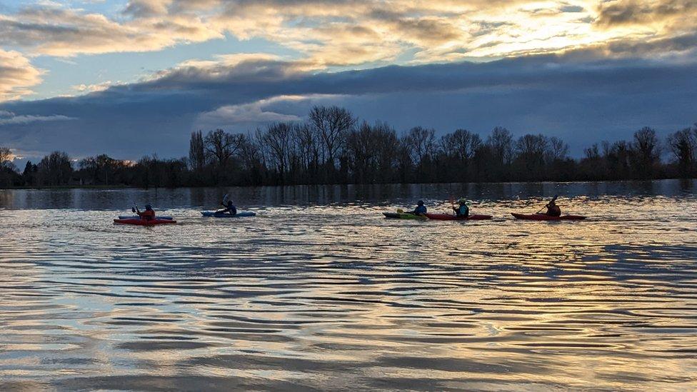 Kayakers paddle across a flooded meadow in St Ives