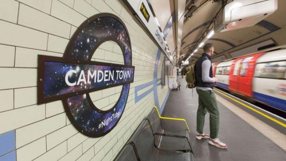 A passenger watches a night tube pass through an underground station