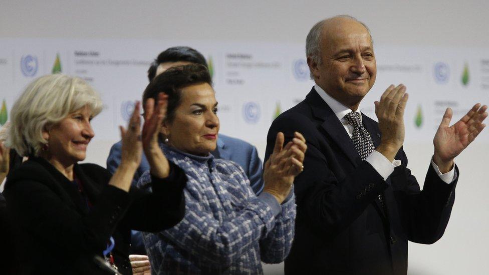 (L-R) French climate change ambassador Laurence Tubiana, executive secretary of the UN Framework Convention on Climate Change Christiana Figueres and French Foreign Minister Laurent Fabius clap after adoption of a historic global warming pact at the COP21 Climate Conference in Le Bourget, north of Paris, on December 12, 2015