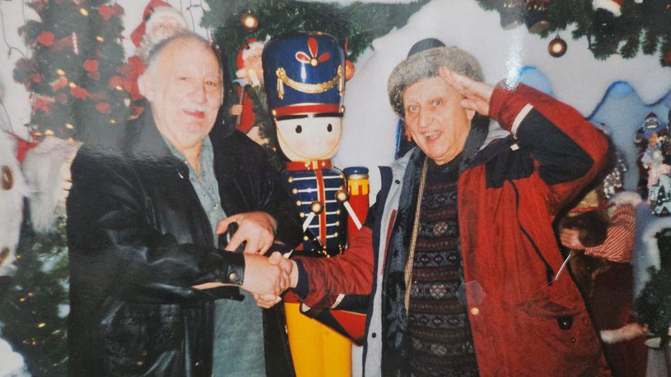 Mr Fullerton is stood in the grotto shaking hands with Ken Dodd. 