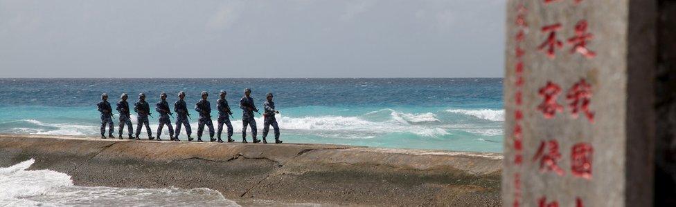 People"s Liberation Army (PLA) Navy patrol near a sign in the Spratly Islands