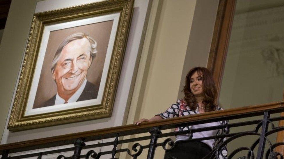 President Cristina Fernandez Kirchner stands in front of a portrait of her late husband and predecessor Nestor Kirchner