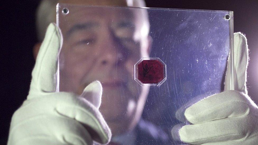 An employee of Sotheby's auction house holds a case containing the sole-surviving 'British Guiana one-cent magenta' stamp dating from 1856, on June 2, 2014 in London, England.