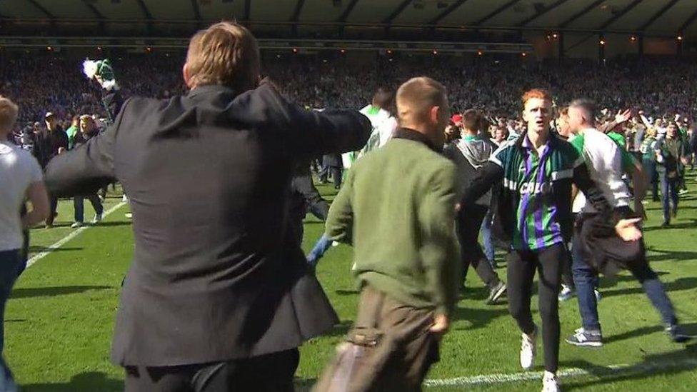 Greg Binnie (right in Hibs top and tracksuit) runs towards Hibs manager Alan Stubbs (left - back to camera)after the pitch invasion