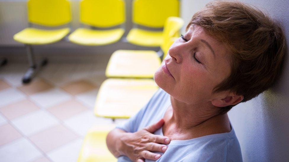 Woman in waiting area holding her chest