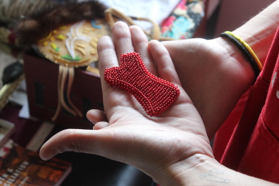 Cambria Harris holds a beaded red dress someone made for her