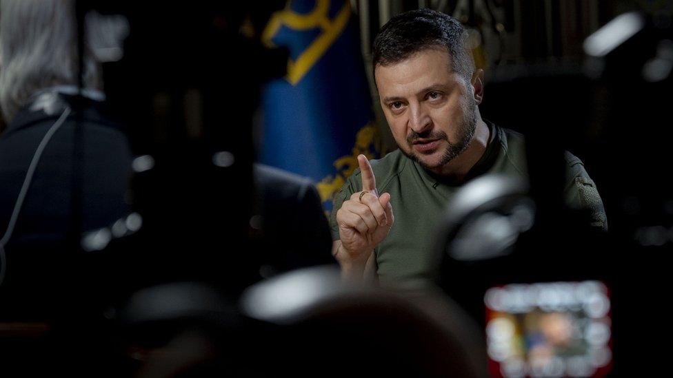 Zelensky gestures with a finger, dressed in his trademark green T-shirt