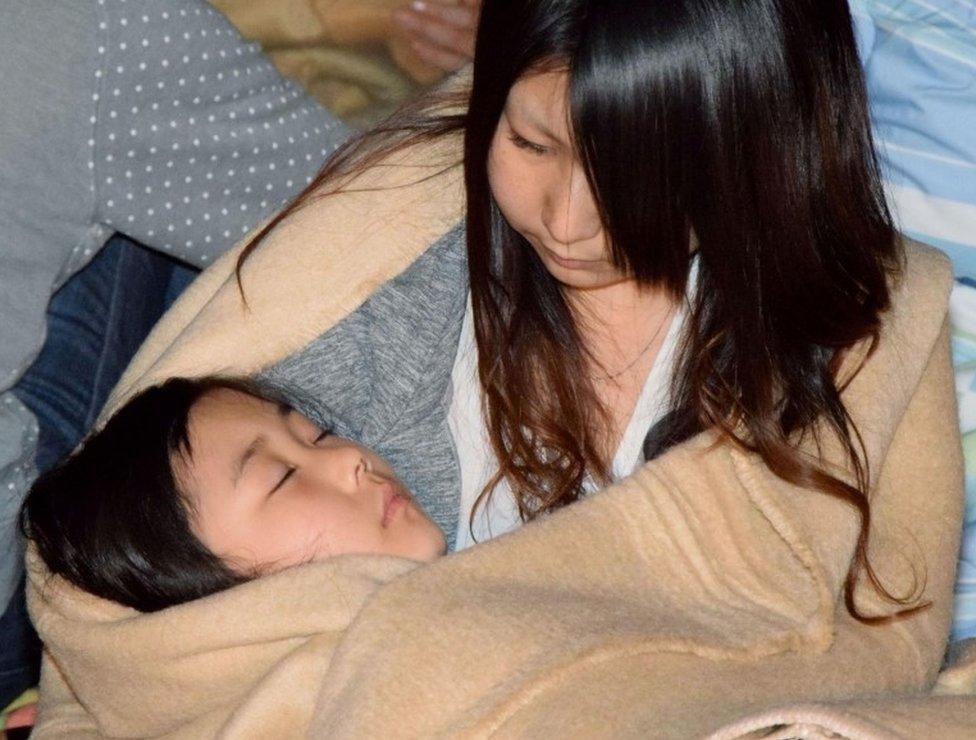 Residents wrap themselves in blankets as they take shelter at the town hall of Mashiki, in Kumamoto, southern Japan, after the earthquake early Friday, April 15, 2016