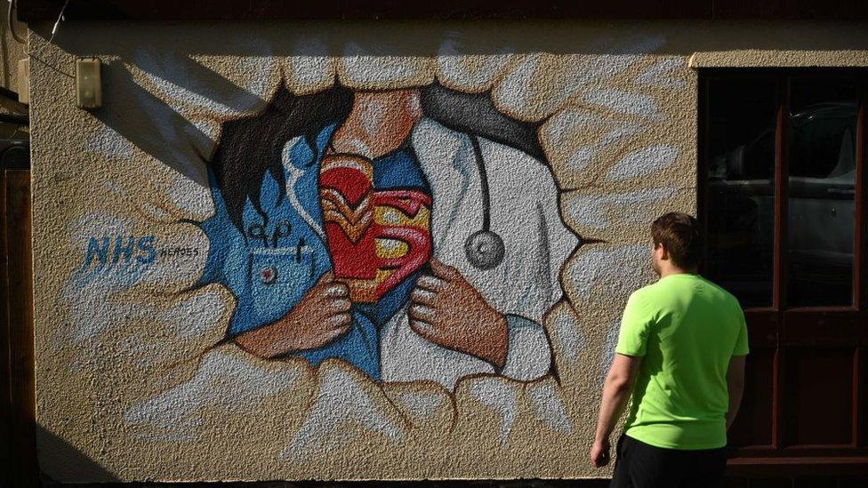 A man looking at NHS superhero street art