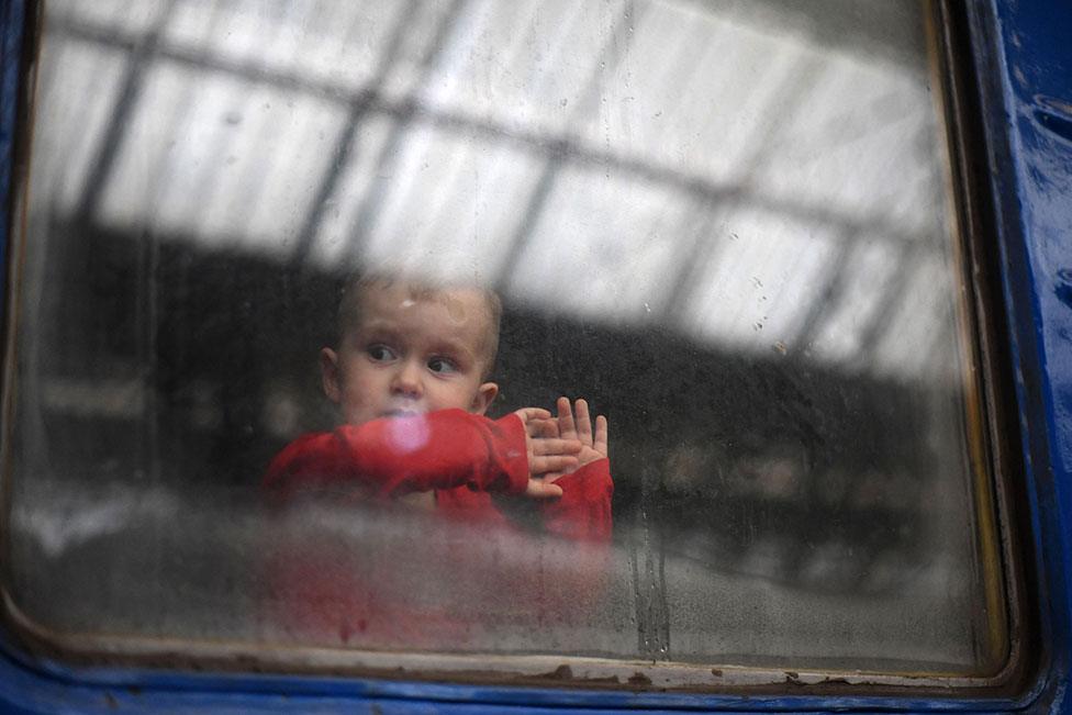 A child looks out from a carriage window as a train prepares to depart from a station in Lviv, western Ukraine, on 3 March 2022