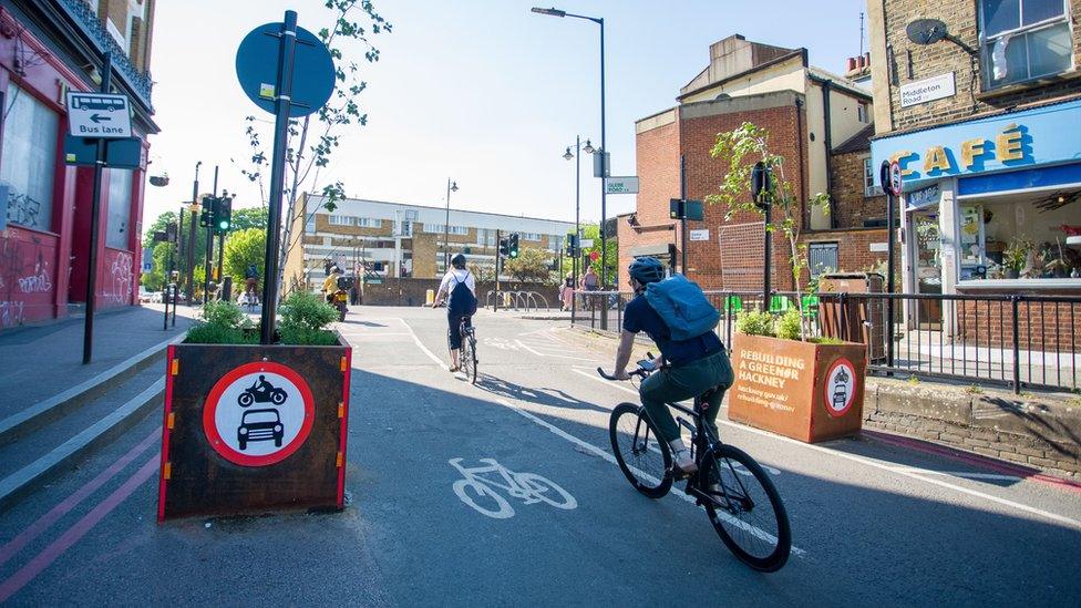 Cyclists ride through barriers marking an LTN on Middleton Road in the borough of Hackney.