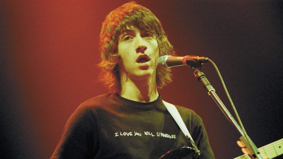 Alex Turner of the Arctic Monkeys wears a t-shirt bearing the graffiti design during a gig