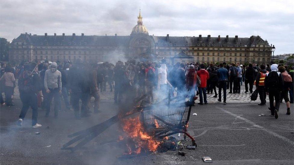 A shopping cart burns as protesters gather near the Invalides during a demonstration against proposed labour reforms in Paris on June 14, 2016.