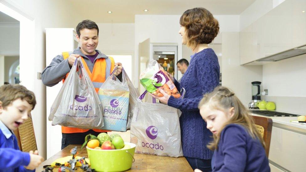 A food deliveryman puts bags of groceries on a table