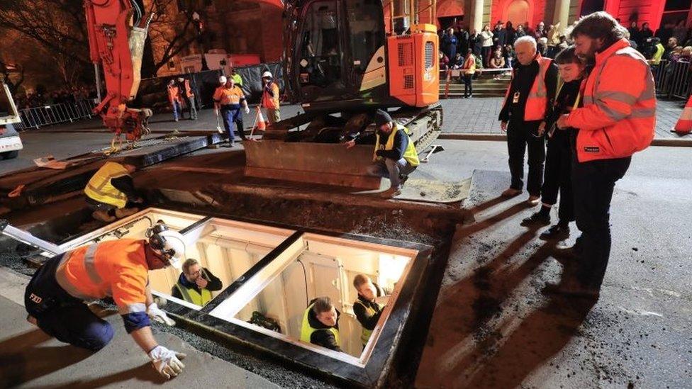 Authorities and festival organisers examine a specially made steel chamber to be used by artist Mike Parr