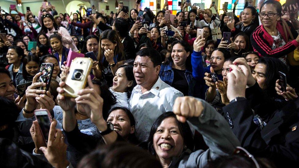 A Rodrigo Duterte impersonator (C), who goes by the name Cresencio Extreme, poses for photos as he attends a church service in the Central district of Hong Kong, 3 February 2019