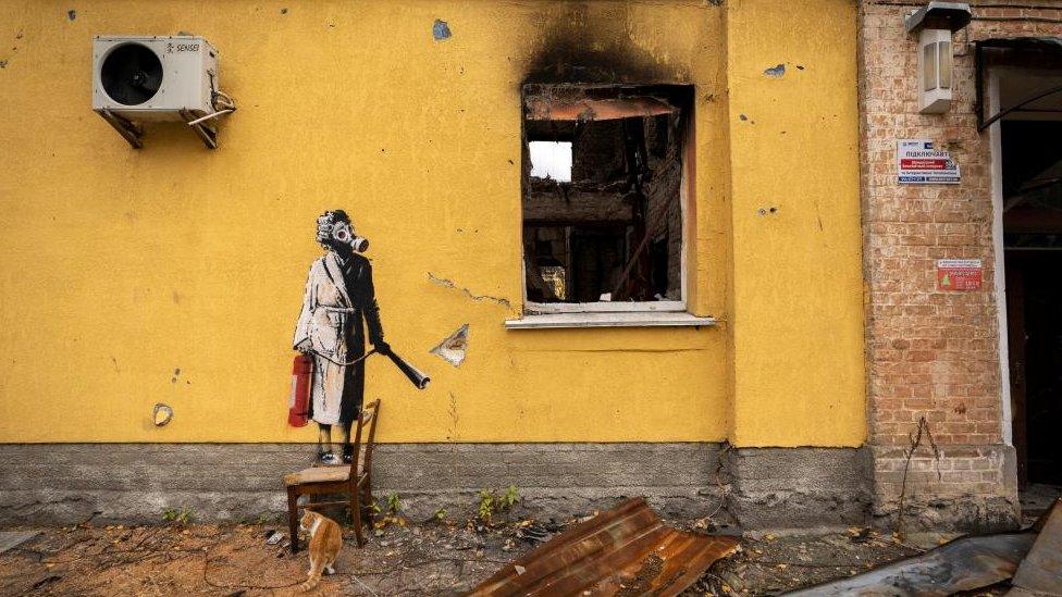 Artwork by Banksy in Ukraine of woman wearing a gas mask and dressing gown