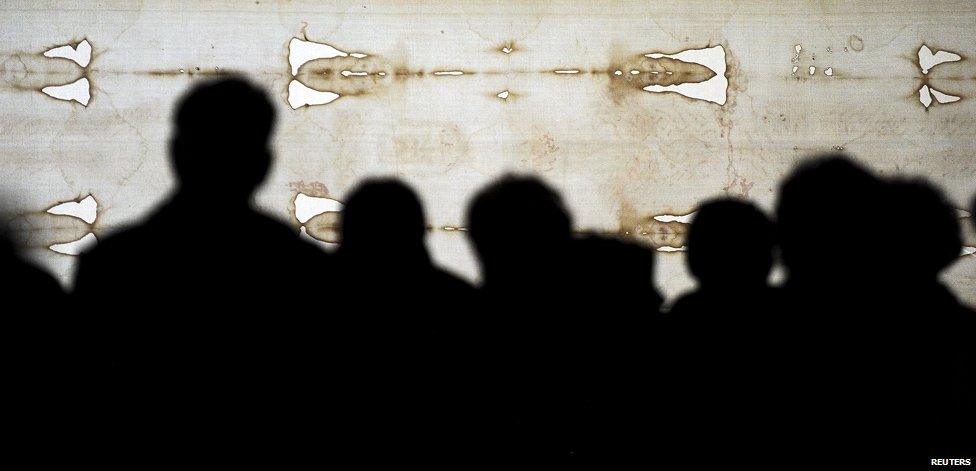 Faithfuls look at the Holy Shroud in the Cathedral of Turin during the opening day of the exposition April 19, 2015