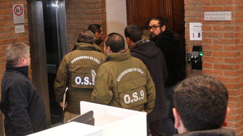 Chilean police officers are seen during the confiscation of the documents inside the office of the Ecclesiastical Court of the archdiocese of Santiago, Chile, June 13, 2018.