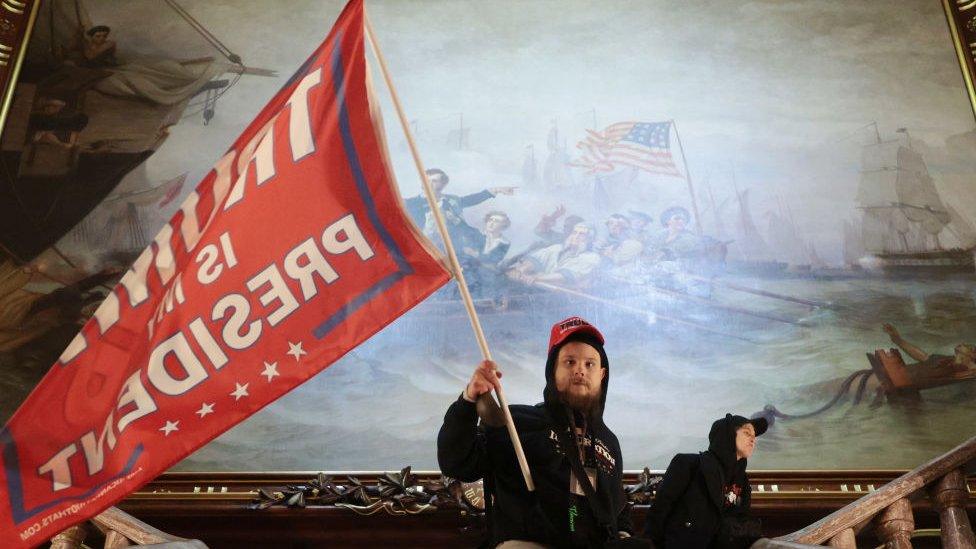 A protester carries a flag that reads "Trump is my president"