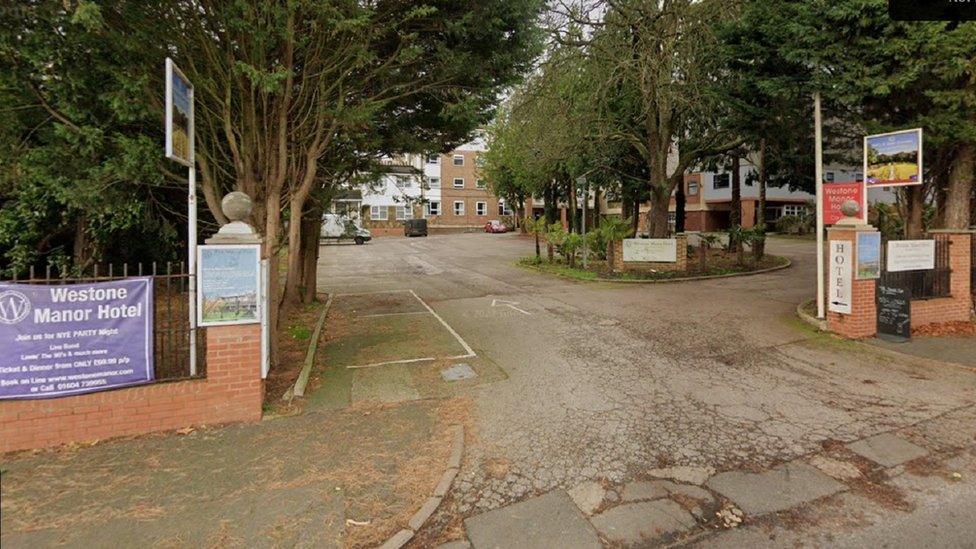 Entrance to hotel, showing trees on either side and Westone Manor Hotel banners