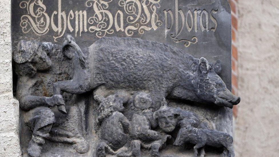 A sculpture from the 13th Century showing a rabbi and two others touching a pig, on the facade of a church in Wittenberg, Germany (4 February 2020)